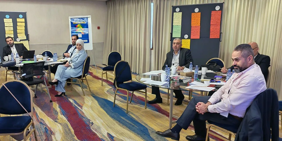 The participants sit at two round tables and listen to the lecture on Damascus.