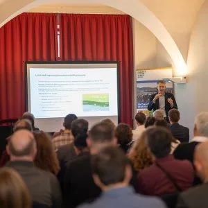 Jan Strehmann is standing to the right of the presentation screen, with the participants' heads in the foreground.
