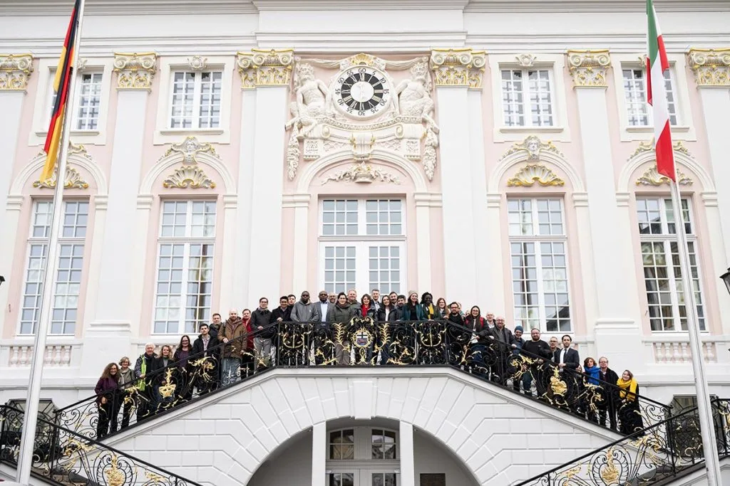 The participants are standing on the steps of Bonn's old town hall.